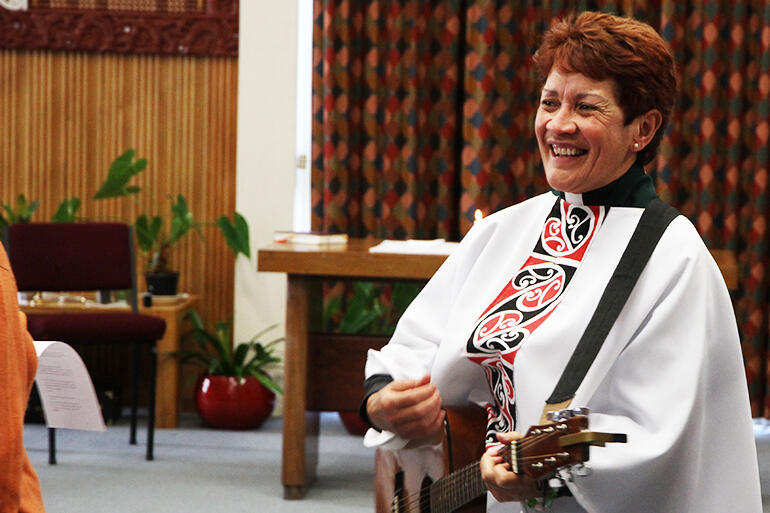 The Rev Numia Tomoana, who presided at the Eucharist, strums her way from the sanctuary.