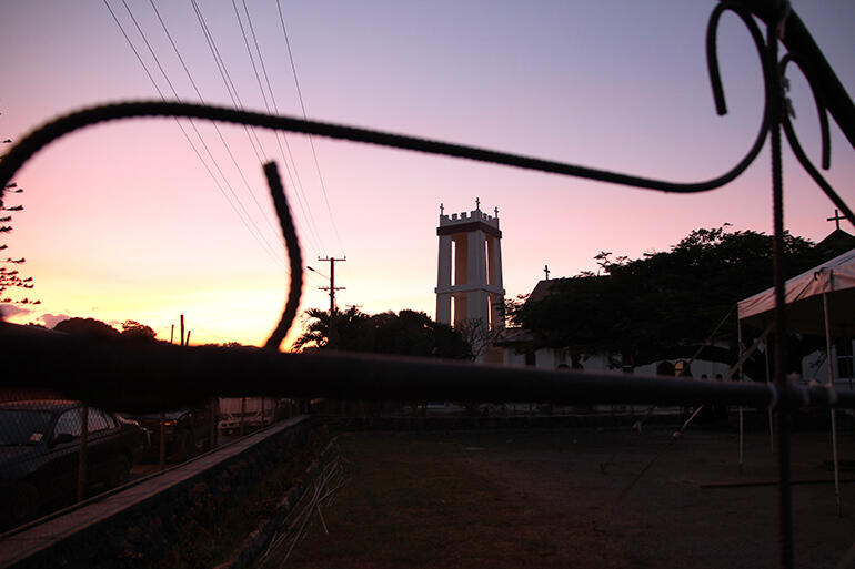 The new St Paul's tower, at dusk, seen through the wrought iron gate to the parking lot next to the church. Marquee at right.