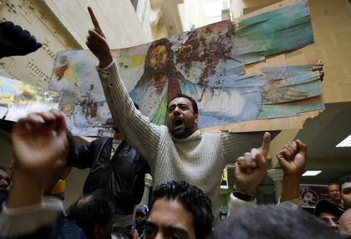 Egyptian Christians hold a bloodstained portrait of Jesus as they protest inside the Al-Qiddissine (The Saints) Church in Alexandria.