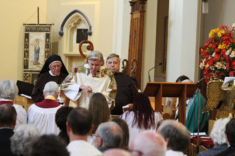 Bishop Victoria Matthews distributes the communion, flanked by Sr Anne SLG and Br Damian SSF.