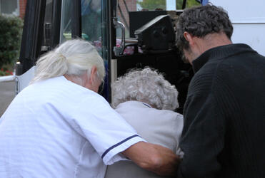 Staff help a resident on to the bus.