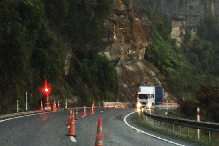 A rain-lashed truck navigates the stretch of State Highway 3 where falling boulders had recently killed a passenger in a passing car.