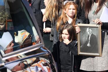 One of Sir Paul's mokopuna watches as lies in the hearse. Archbishops Moxon and Sentamu are reflected in the hearse window.