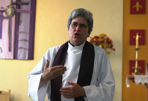 Holy Trinity Vicar Marge Tefft invites people to communion, and to express their grief and hope in symbolic form
