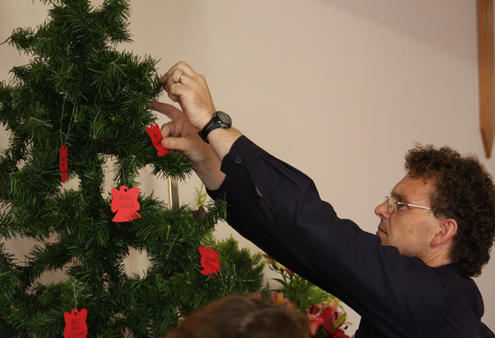 Tim Mora decorates the tree at Cobden's Church of the Resurrection. The angels recall the ones who won't be home for Christmas.
