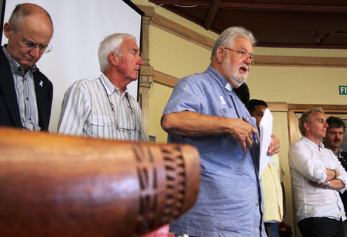 Rev Tom Van Culin, from Hawaii, reports from the men's caucus. Ian Sparks (left) and John Rea (both from the UK) stand in support.