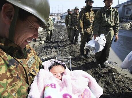 A rescuer weeps for joy as he cradles a 4-month-old child found alive after three days in a ruined house in northern Japan. Photo: AP