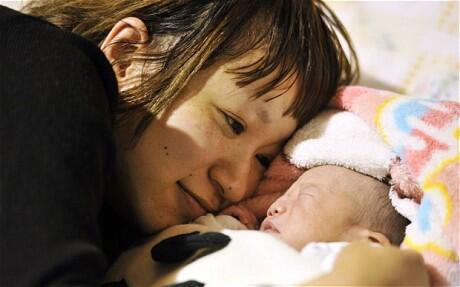 An unidentified mother watches her baby who was born on March 12 at a shelter in Iwaki, Fukushima. Photo: Reuters