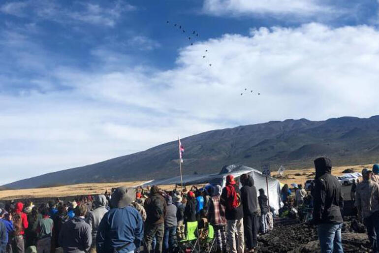 Visitors look toward the summit of Maunakea, the sacred mountain of the kanaka maoli people. Photo: Ryan Finnerty/HPR Visitors look toward the summit of Maunakea, the sacred mountain of the kanaka maoli people. Photo: Ryan Finnerty/HPR