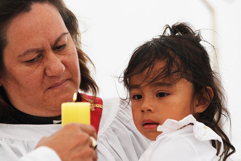Kahira Rau holds Sophia Palaamo as she's presented with her baptismal candle.