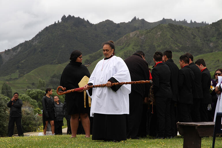 Jackie Chesley-Ingle and the pallbearers pause at Tuatini Marae before processing to the urupa.