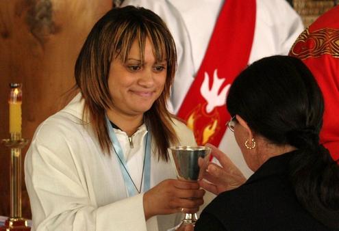 Hayley Mitchell, Manu Karakia, offers the chalice to Catherine Teller, Michael Tamihere's mother.