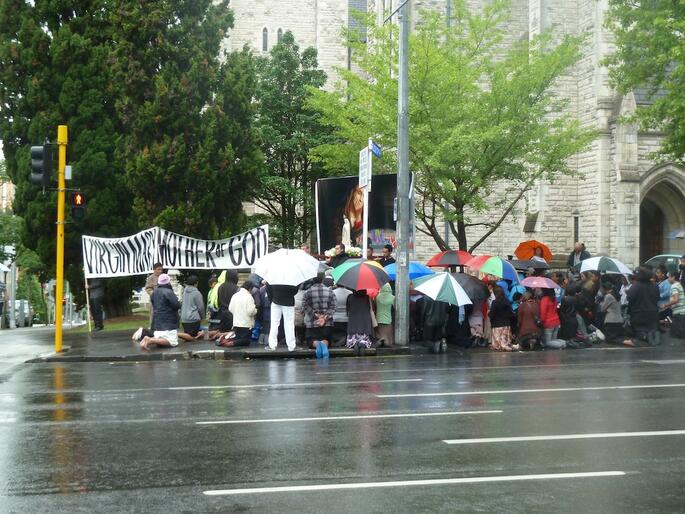 Billboard protesters kneel in prayer outside St Matthew-in-the-City. Billboard protesters kneel in prayer outside St Matthew-in-the-City.
