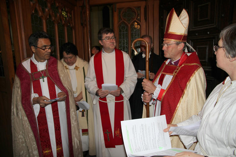 Archdeacons meet the new bishop at the door.