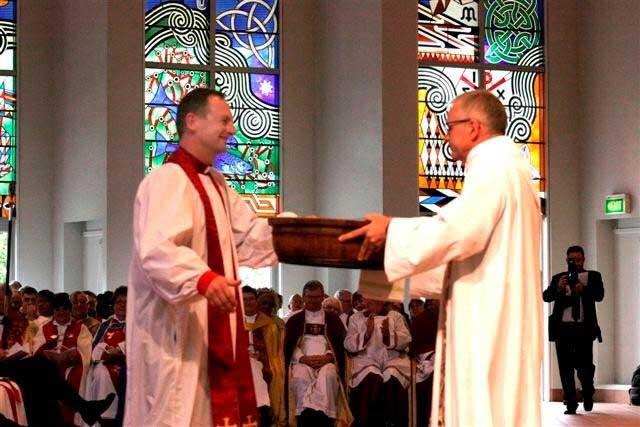 Preacher Jim White hands the new bishop two essential tools of office: a basin and towel. Preacher Jim White hands the new bishop two essential tools of office: a basin and towel.