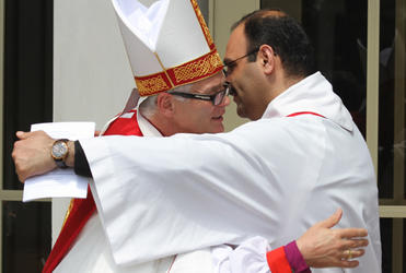 Rev George Al-Kopti embraces the new bishop. Fr George is a Palestinian priest studying for his doctorate at St John's College.