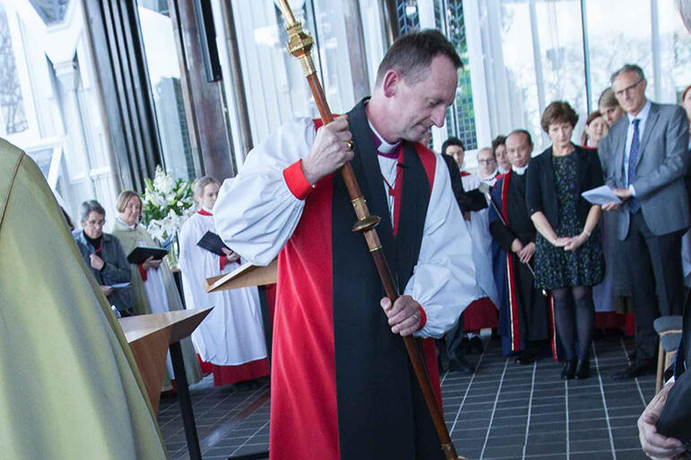 Bishop Ross Bay uses his crozier to trace the letters Alpha and Omega on the floor as he dedicates the new chapel.