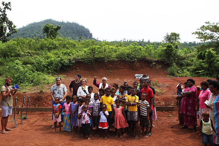 Archbishop Winston with the children of Maniava. He's preparing to bless the earthworks for the new church.