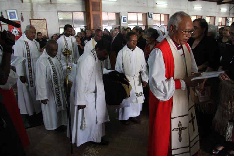 Bishop Winston Halapua leads the pallbearing priests from the cathedral.