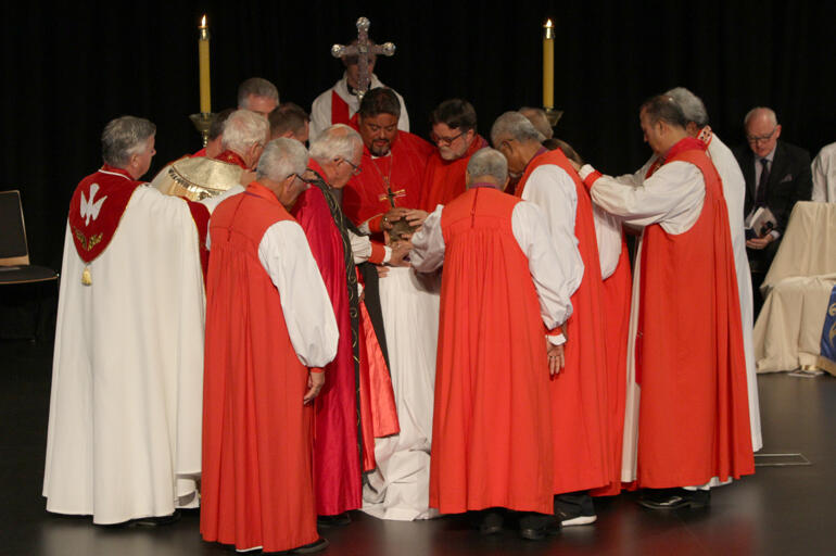 Bishops encircle Peter to ordain him bishop in the laying on of hands.
