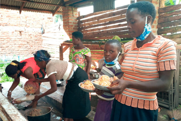 Women and children eat nutritious food provided by the Rwenzori Special Needs Foundation in Uganda.