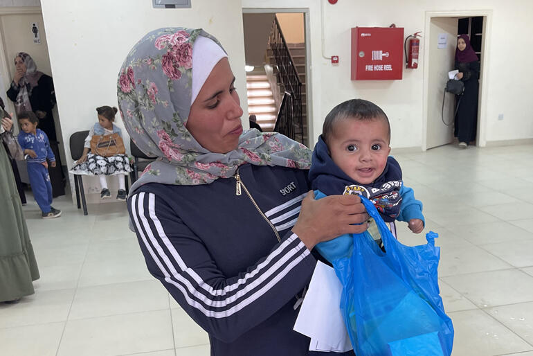 Baby Ahmed and his mum collect their baby kit at the Well Baby Clinic in Madaba Palestinian Refugee Camp, Jordan in 2023.