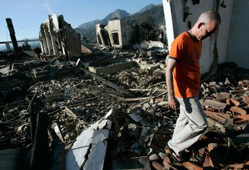 Brother Joseph Brown walks through the rubble of his monastery after it was levelled by fire. Picture, Los Angeles Times.