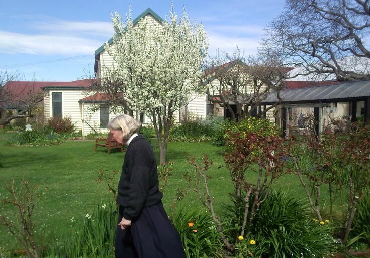 Bishop Victoria walks past the blossoming Victoria Plum tree in the convent's enclosed garden.