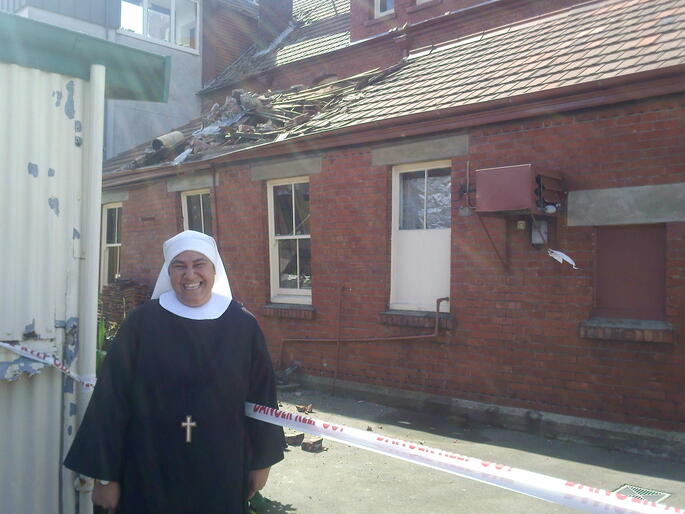 Sister Sandra, CSN, outside the convent's condemned laundry block. Note the damage done by the fallen chimney.