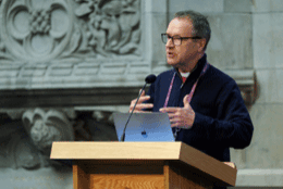 Bishop Graham Tomlin stands at a podium during te global Anglian ACC meeting