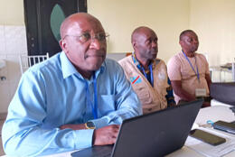 Three African men sit at laptops in a meeting 