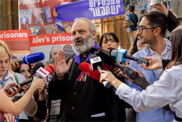Archbishop Bagrat Galstanyan middle aged bearded Armenian man speaks to a crowd of reporters from a protest on refugee rights