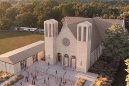A brick cathedral with two towers sits alongside a parish centre and grassy field