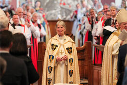 Bishop Cherry Vann smiles in cope amid applauding bishops