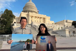 A Chinese man and woman stand with photos of church pastors before the US state capitol building