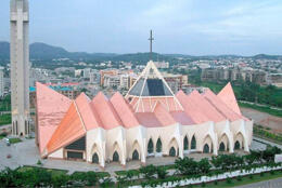 Aerial view of a modern cathedral with fanned arc roofing standing in a Nigerian city landscape