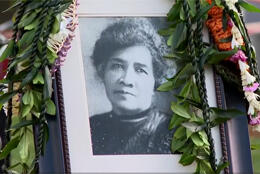 A framed black & white picture of a middle-aged Hawaiian woman with 19th century hairstyle surrounded by foliage