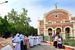 Indian acolytes and clergy stand outside a brick Catholic church