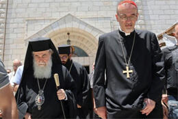 Roman Cardinal in black cassock and Greek Orthodox Patriarch in black robe, hat and veil outside Gaza church