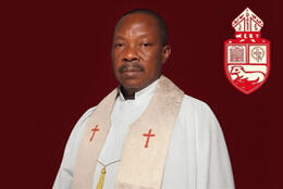 Portrait: a middle aged African priest wearing white alb & stole 