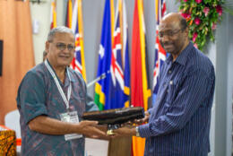 A Samoan man (congregationalist elder Dr. Leatulagi Faalevao) hands a carved wooden slot drum to WCC's Indian Gen Secretary Rev Dr Jerry Pillay 