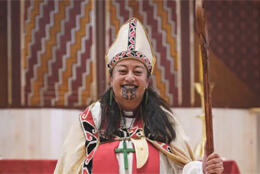Bishop Susan Wallace stands in cope and mitre before a tukutuku panel at Christchurch Transitional Cathedral