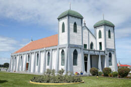 Twin green-domed towers front a white painted church at Ratana