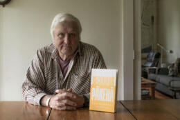 Retired Bishop John Bluck sits behind a copy of his book, 'Becoming Pākehā'