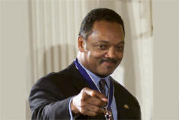 An African American man in his 50s smiles and points towards the camera