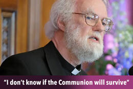 Former Archbishop of Canterbury Grey haired and bearded Rowan Williams in a black clerical shirt speaking at a podium