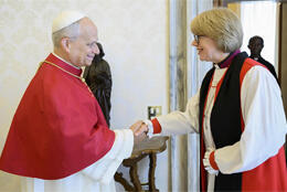 Pope Leo and Archbishop of Canetrbury Sarah Mullally, both in red and white episcopal robes shake hands in a Vatican meeting room