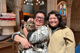 A priest kneels and talks to whānau with cats and dogs