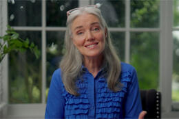 A long-haired female presenter smiles into the camera