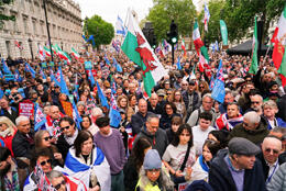 Thousands throng a street protest with union jacks and red, white and green flags